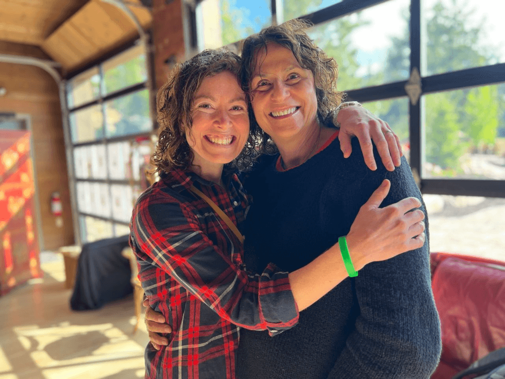 Cat and JoAnn embracing and laughing together at a retreat