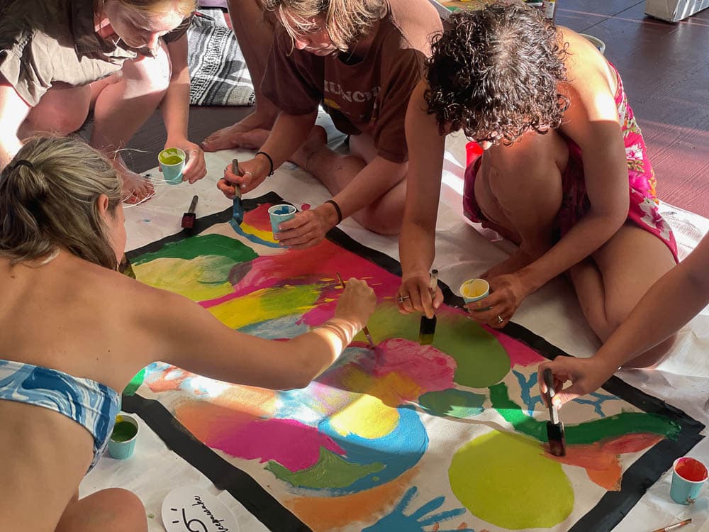 Campers painting together on a shared canvas